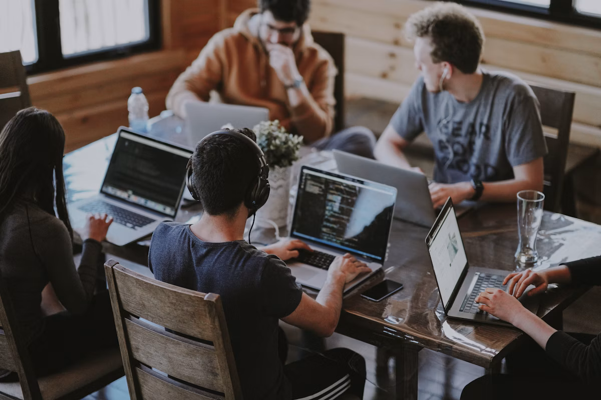 Stock photograph of colleagues collaborating around a table with laptops